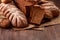 Freshly baked bread loaves on burlap on wooden table with wheat. Texture closeup bakery products