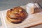 Freshly baked bun with a crispy crust and a glass of milk on a cutting board close-up.