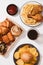 Freshly baked buns, big hamburger, fried crispy chicken and french fries on white table - Unhealthy food concept