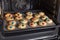 Freshly baked cookies with color sweets on tray in oven.