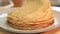 Freshly baked crepes, adding a new crepÐµ to the stack. Hot crepes with actively rising steam