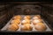 freshly baked crispy buns in the oven on the tray, process of cooking mini small bread