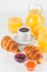 Freshly baked croissant, orange juice, fresh fruits, jam on white wooden background. French breakfast. Fresh pastries for morning.