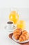 Freshly baked croissant, orange juice, fresh fruits, jam on white wooden background. French breakfast. Fresh pastries for morning.