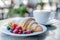 Freshly baked croissant with summer berries, served with cappuccino at a lovely outdoor street cafe