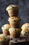 Freshly baked crumble muffins with wild bilberries arranged in unstable pile on dark background copy space. Low key still life