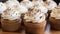 Freshly baked cupcakes with cream cheese frosting and cinnamon sprinkle on white table