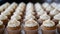 Freshly baked cupcakes with cream cheese frosting on a white table, sprinkled with cinnamon