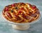 Freshly Baked Fruit Tart on Elegant Cake Stand Against Blue Textured Background for Culinary Presentation