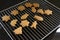 Freshly baked gingerbread cookies for Christmas cool down on a metal baking grid over a black background