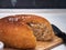 Freshly baked homemade round-shaped bread is notched, it lies on a wooden board. Subject shot close up with soft focus.