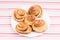 Freshly baked homemade snail buns with sugar and cinnamon on white plate and striped tablecloth. Balanced nutrition, proteins and