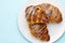 Freshly baked italian croissants on a white plate on the blue background with copy space. Concept of advertisement of