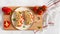 Freshly baked italian piadina with cheese, tomato, ham, red pepper and basilio on a white plate on a white wooden table. Top view