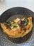 Freshly baked omelette filled with porcini mushrooms and baby spinach in a pan