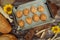 Freshly baked pies, buns on baking sheet and crusty bread, rolling pin, sunflower and ears of wheat on brown wooden background