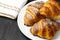 Freshly baked plain croissants on a white plate near serviette on a black wooden background. Homemade french pastry.