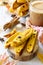 Freshly baked raisins and cinnamon biscotti and a cup of cappuccino coffee on a gray slate or slate background