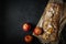 freshly baked rectangular apple cake with whole apples and ears on paper and a cutting board on a textured dark background. top