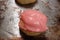 A freshly baked Russian Tea Cookie topped with pink frosting