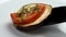 A freshly baked slice of eggplant with a piece of tomato and cilantro is placed on a white ceramic plate.