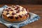 Freshly baked small cherry cake with almond slivers, rustic wood and dark background with copy space