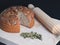 A freshly baked sourdough bread with pumpkin seeds and a rolling pin on a wooden surface