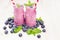 Freshly blended violet blueberry fruit smoothie in glass jars with straw, mint leaves, berries.