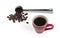 Freshly brewed coffee with foam  in a red cup and a steel measuring spoon with roasted coffee beans