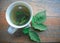 freshly brewed raspberry leaf tea in a white cup and a fresh raspberry leaf