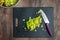 Freshly chopped celery on a black cutting board, chef knife, wood table