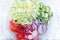 Freshly chopped summer salad. Many delicious vegetables in glass salad bowl - cucumber, lettuce, radish, tomatoes, red onion