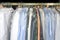 Freshly cleaned men`s shirts and ladies blouses in a dry cleaning, hung on hangers and protected by plastic film.