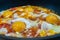 Freshly cooked appetizing fried eggs with red sweet tomatoes in a hot pan. Delicious homemade food