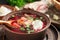 Freshly cooked borscht - traditional dish of Russian and Ukrainian cuisine in earthenware dishes with bacon, bread, sour