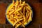Freshly cooked french fries on plate on stone background. Top view