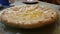Freshly cooked hot Ossetian pie with cheese is on the kitchen table. The fat butter melted on the dough. Delicious hearty dinner