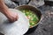 Freshly cooked hot soup in old cauldron on camp fire and man hand with pot cover