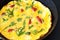 Freshly cooked omelet with herbs and tomatoes on rustic metal pan