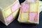 Freshly cut Battenberg Cake on dark slate board. Pink and yellow sponge covered in marzipan