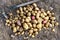 Freshly dug up heap of red and yellow potatoes lying on soil next to hoe from above.