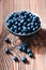 Freshly gathered blueberries put into ceramic bowl. Some fruits freely scattered