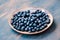 Freshly gathered blueberries put on old ceramic plate. Table painted in blue