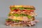 Freshly made deli style sandwich with lettuce, several different kinds of vegetables, tomatoes, cheese, meats similar to ham,