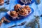 Freshly made homemade muffins on a blue plate with walnuts with fir branches lying ne xt to