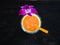 Freshly made multi fruit orange smoothie from various tropical fruits in a glass beaker decorated with an orchid flower on a dark