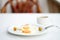 Freshly made scrambled eggs served with two green olives on a white dish, on a table with a white tablecloth with a cup of coffee