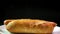 Freshly made steaming hot dog against black background. Popular fast food 4K closeup dolly video