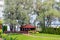 Freshly mowed rows of green lawn at country residence with summerhouse. Fence hedge of fresh thuja cedars. Landscaping