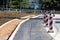 Freshly paved road still under construction filled with stripped red and white warning road signs surrounded with new concrete